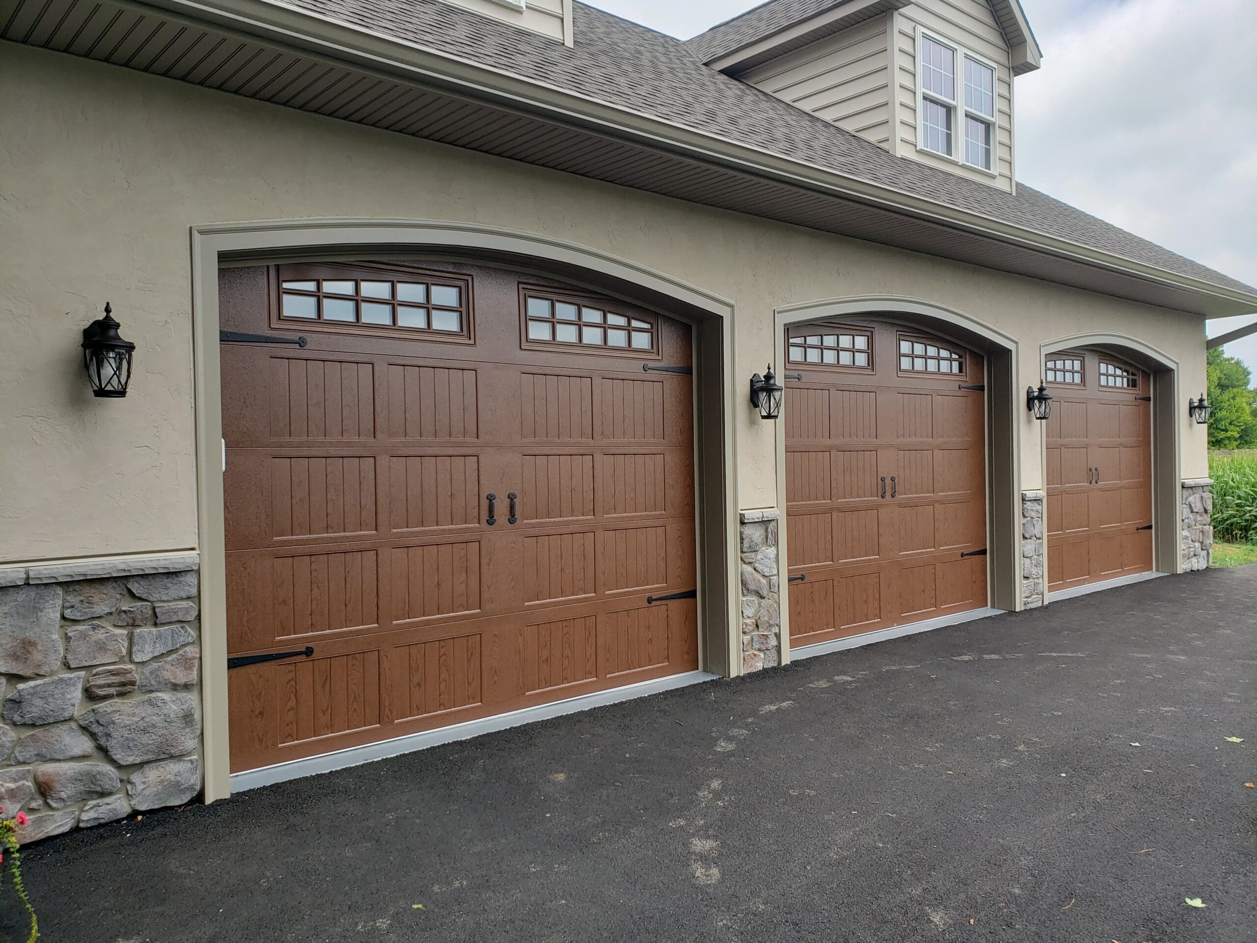 A brown garage door with a stone driveway.